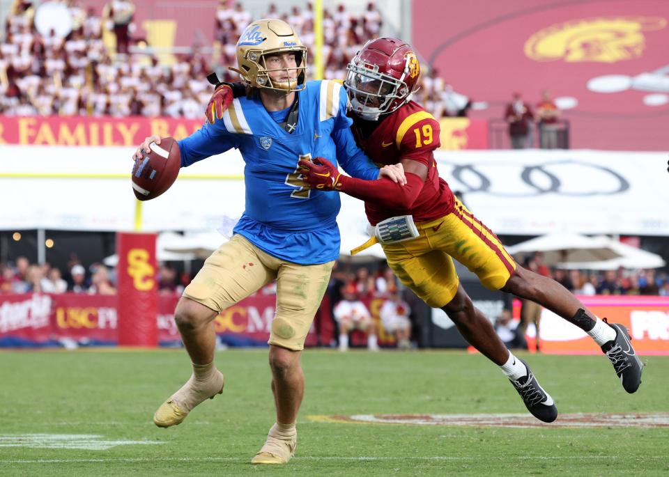 UCLA quarterback Ethan Garbers (4) scrambles to throw while under pressure from Southern California safety Jaylin Smith (19) during their game at United Airlines Field at Los Angeles Memorial Coliseum.