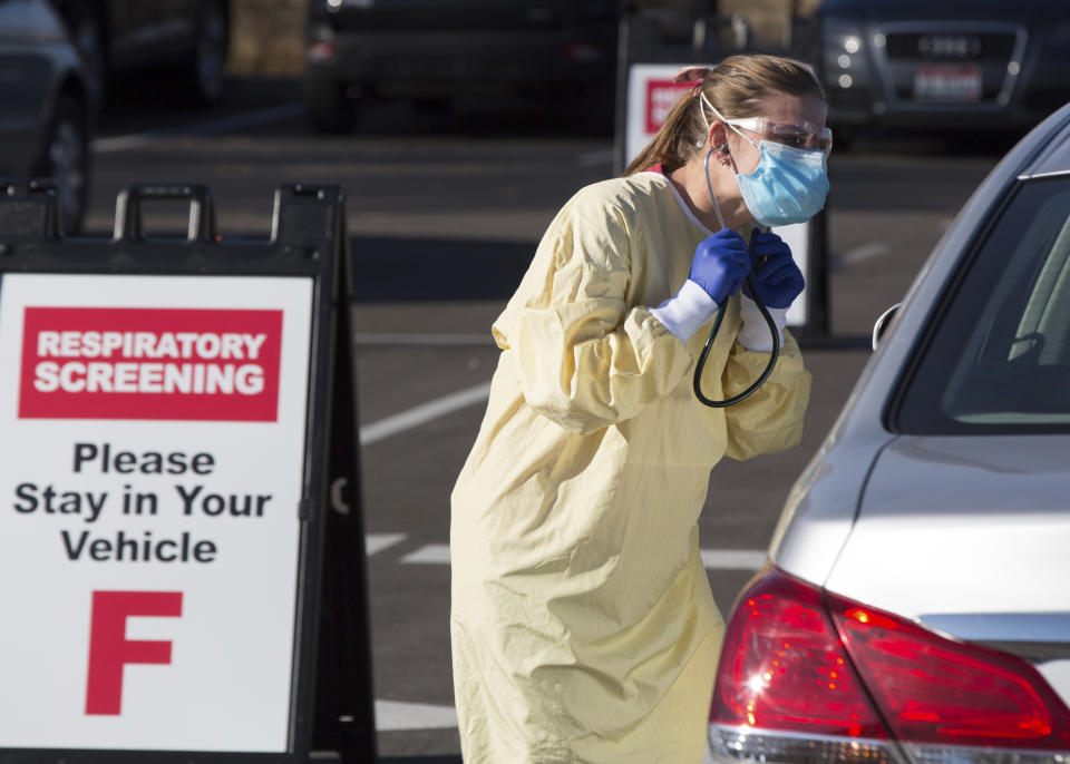 Physician assistant Nicole Thomas conducts a COVID-19 examination in the parking lot at Primary Health Medical Group's clinic in Boise, Idaho, Tuesday, Nov. 24, 2020. The urgent-care clinic revamped into a facility for coronavirus patients as infections and deaths surge in Idaho and nationwide. Some 1,000 people have died due to COVID-19, and infections this week surpassed 100,000. (AP Photo/Otto Kitsinger)