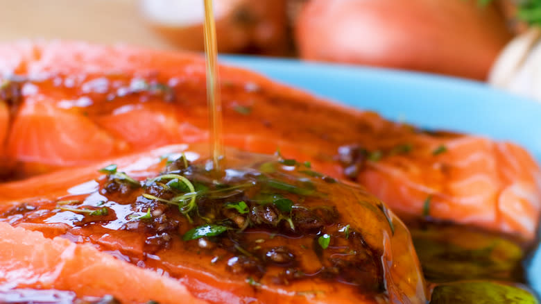 Person pouring marinade over salmon