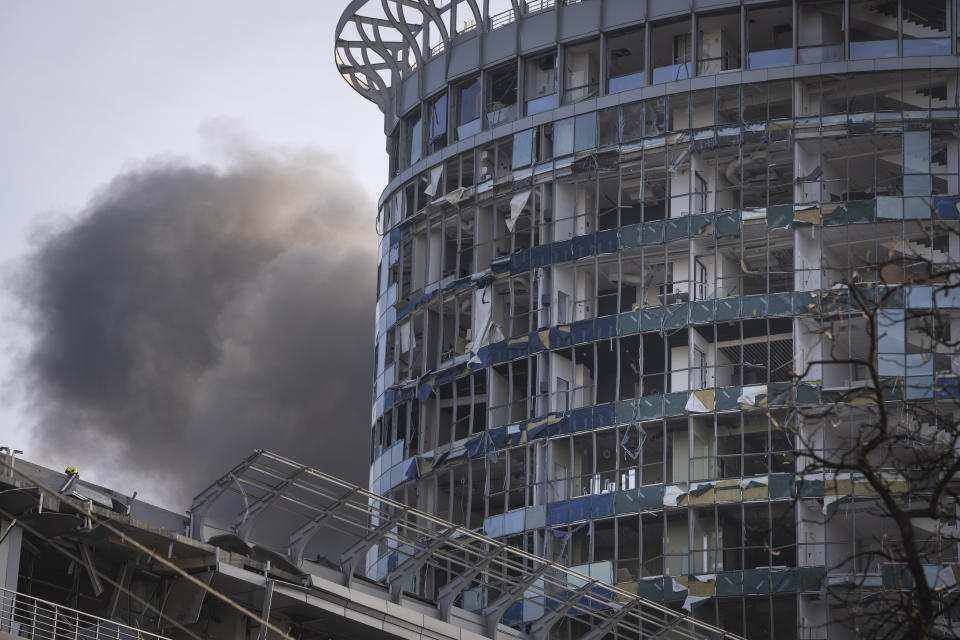 Smoke rises behind a building damaged in Russia's missile attack in Kyiv, Ukraine, Friday, Dec. 29, 2023. Russia launched about 110 missiles as well as drones against Ukrainian targets during the night Ukraine President Volodymyr Zelenskyy said Friday, in what appeared to be one of the biggest aerial barrages of the 22-month war.(AP Photo/Efrem Lukatsky)