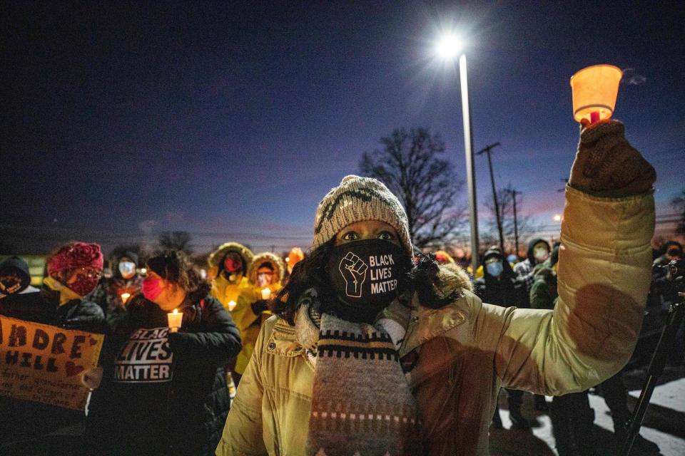 A woman wearing a Black Lives Matter mask raises a candle during a candlelight vigil to honour Andre Hill's memory outside the Brentnell Community Recreation Center in Columbus, Ohio on December 26, 2020. (Stephen Zenner/AFP via Getty Images)