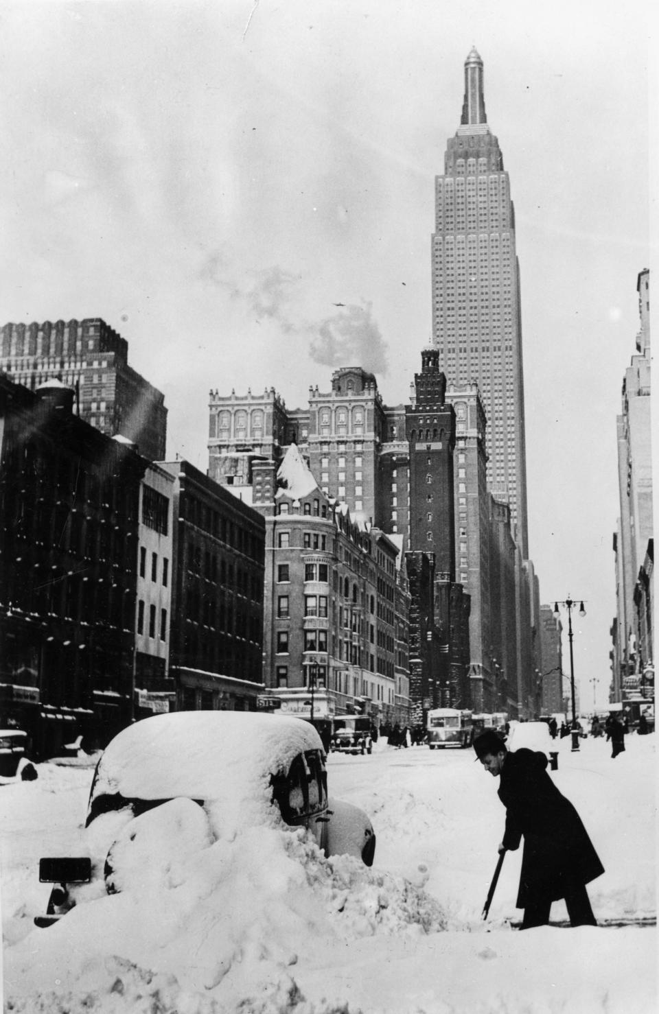 After a surprising snowstorm a driver is clearing the way near the Empire State Building in 1930. 