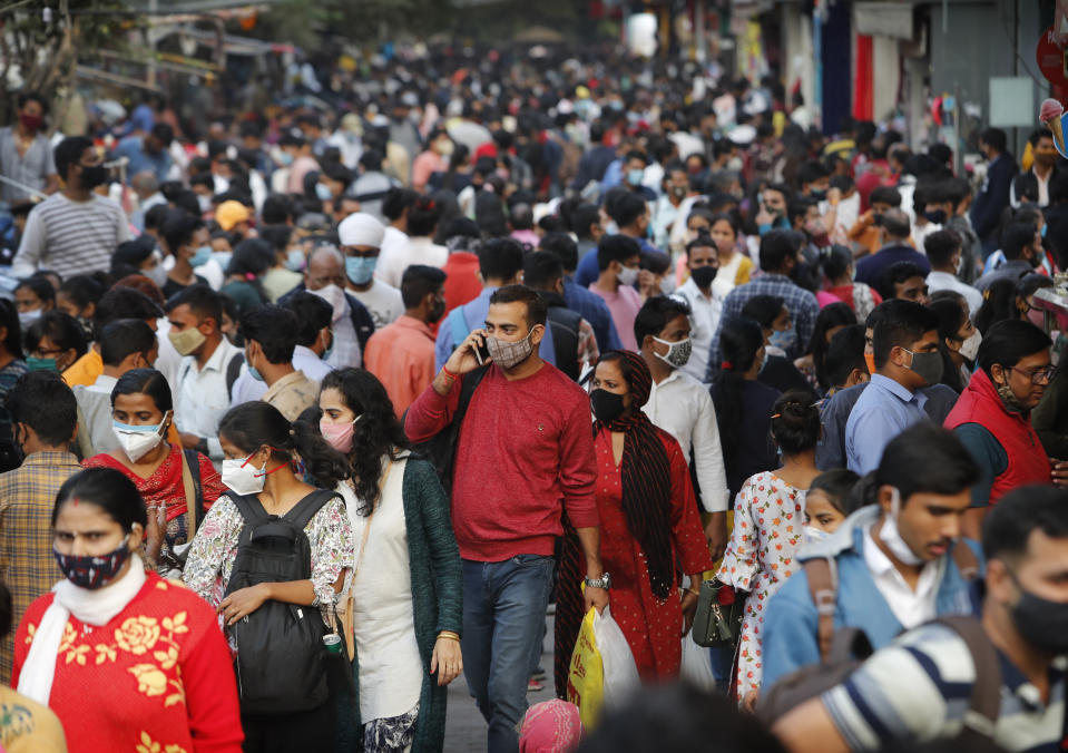 FILE - In this Nov. 12, 2020, file photo, people walk in a market to shop ahead of the Diwalli festival in New Delhi, India. Scientists say it's still too early to predict the future of the coronavirus, but many doubt it will ever go away entirely. (AP Photo/Manish Swarup, File)