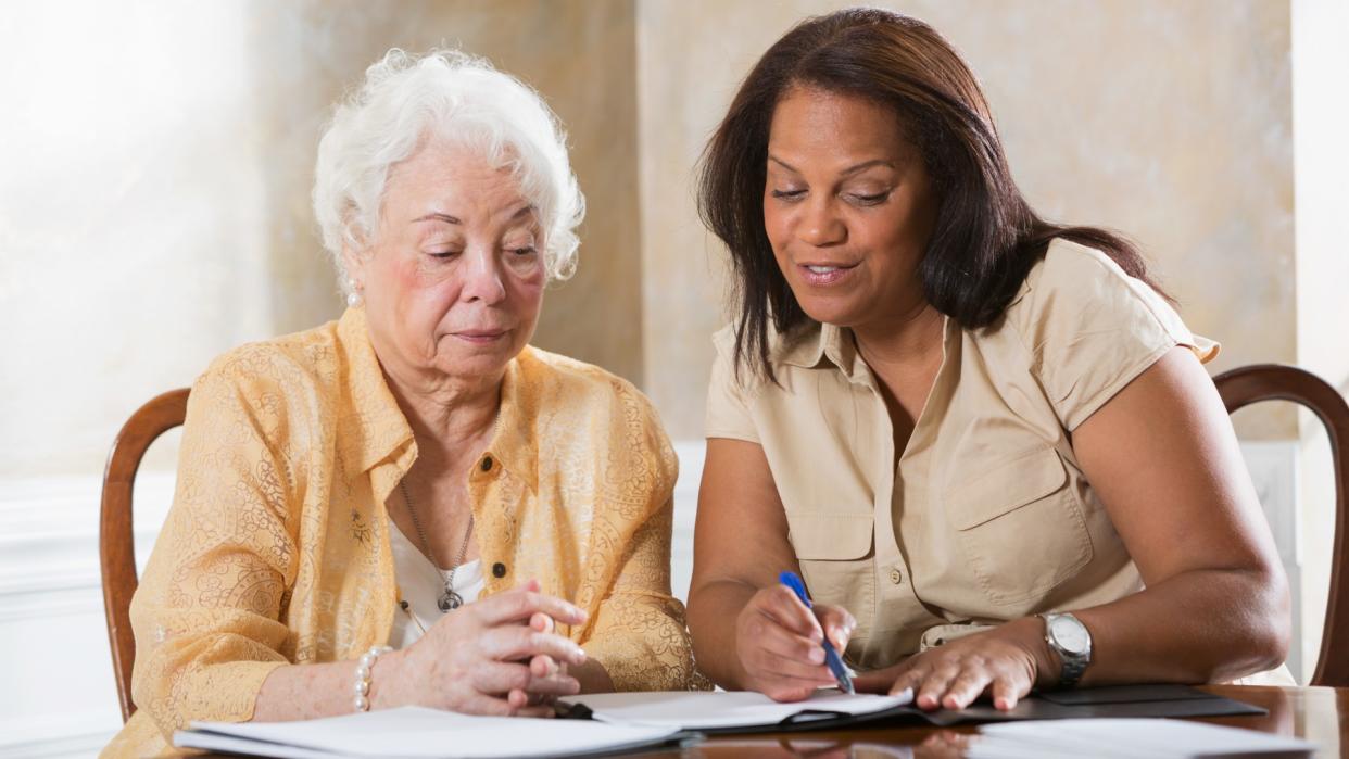 Mature Hispanic woman (50s) advising senior Hispanic woman (70s).