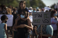 Israeli social workers hold signs during a demonstration against the economic situation in the central Israeli town of Kfar Ahim, Thursday, July 9, 2020. Hebrew reads: "No Country without social services." With a new outbreak of coronavirus devastating Israel's economy, one of Prime Minister Benjamin Netanyahu's closest confidants was dispatched on to a TV studio on a recent day to calm the nerves of a jittery nation. Instead, he dismissed the public's economic pain as "BS."(AP Photo/Sebastian Scheiner)