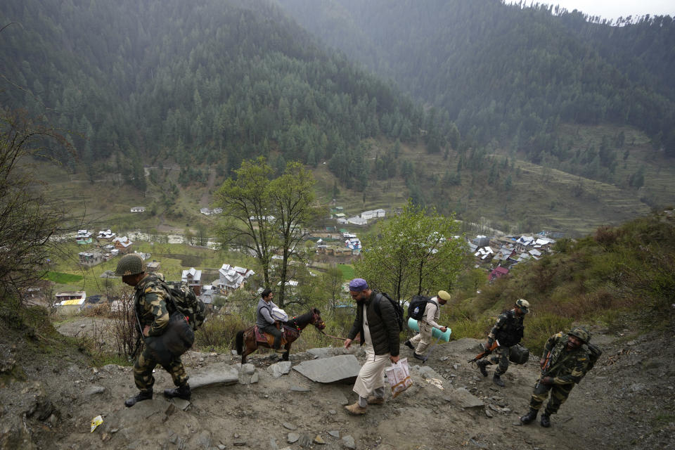 A man transports electronic voting machine on a pony as election officials walk to a polling booth in a remote mountain area on the eve of the first round of voting in the six-week long national election at Dessa village in Doda district, Jammu and Kashmir, India, April 18, 2024. (AP Photo/Channi Anand)