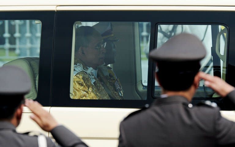 Thai King Bhumibol Adulyadej sits in his royal limousine along with his son and Crown Prince Maha Vajiralongkorn as he leaves the Anantasamakom Throne Hall in Bangkok, December 5, 2012. Television images showed a sea of supporters of the revered king, many wearing yellow symbolising Monday, the day of his birth, and waving royal and Thai flags