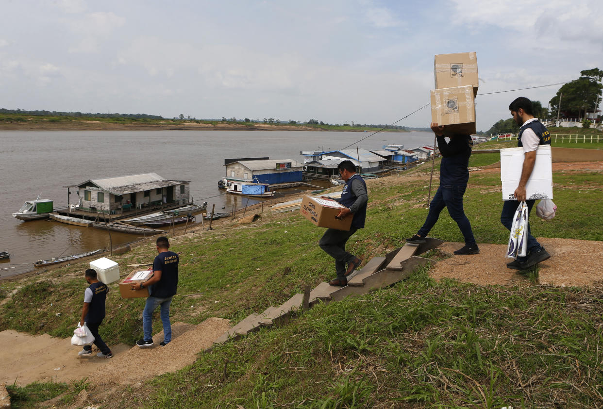 Electoral workers carry electronic voting machines and election materials, to be taken by boat to polling stations a day ahead of the country's presidential runoff election, in Autazes, Amazonas state, Brazil, Saturday, Oct. 29, 2022. (AP Photo/Edmar Barros)