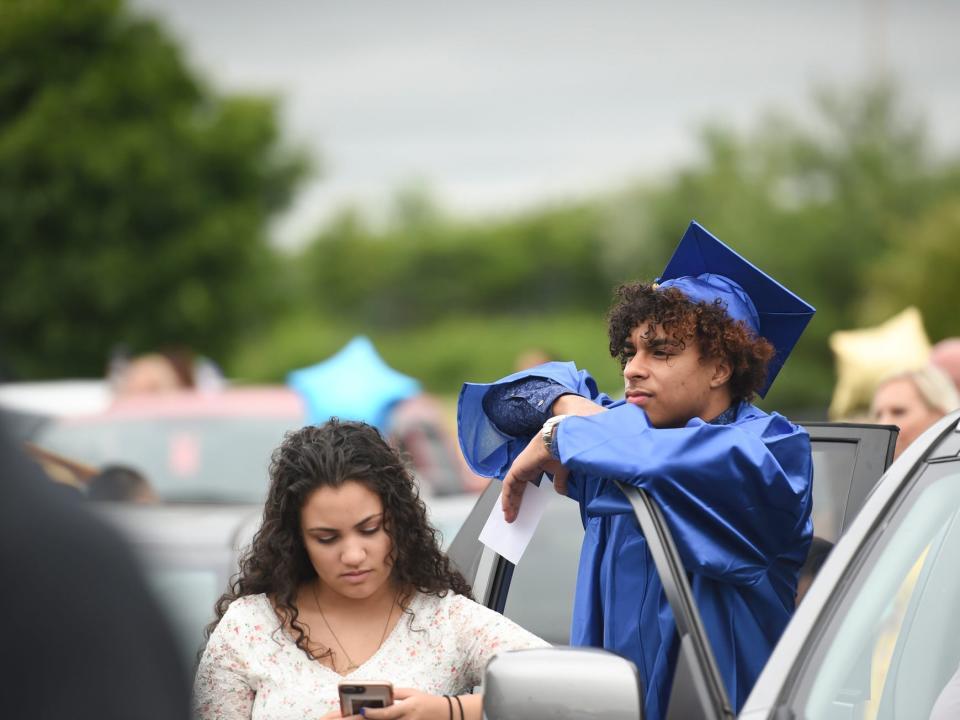Graduate Jarameel Perez hangs out the door of his car while listening to Muhlenberg High School's drive-in graduation ceremony Thursday morning.