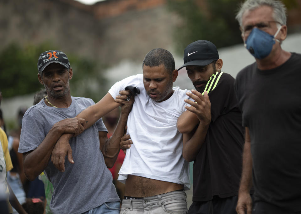 Alexsandro dos Santos, center, is helped by friends during the burial of his 4-year-old daughter Emily Victoria Silva dos Santos, at a cemetery in Duque de Caxias, Rio de Janeiro state, Brazil, Saturday, Dec. 5, 2020. Grieving families held funerals for Emily and her 7-year-old cousin Rebeca Beatriz Rodrigues dos Santos, killed by bullets while playing outside their homes. Weeping and cries of “justice” were heard Saturday at their funerals, reflecting the families’ assertion that the children were killed by police bullets. (AP Photo/Silvia Izquierdo)