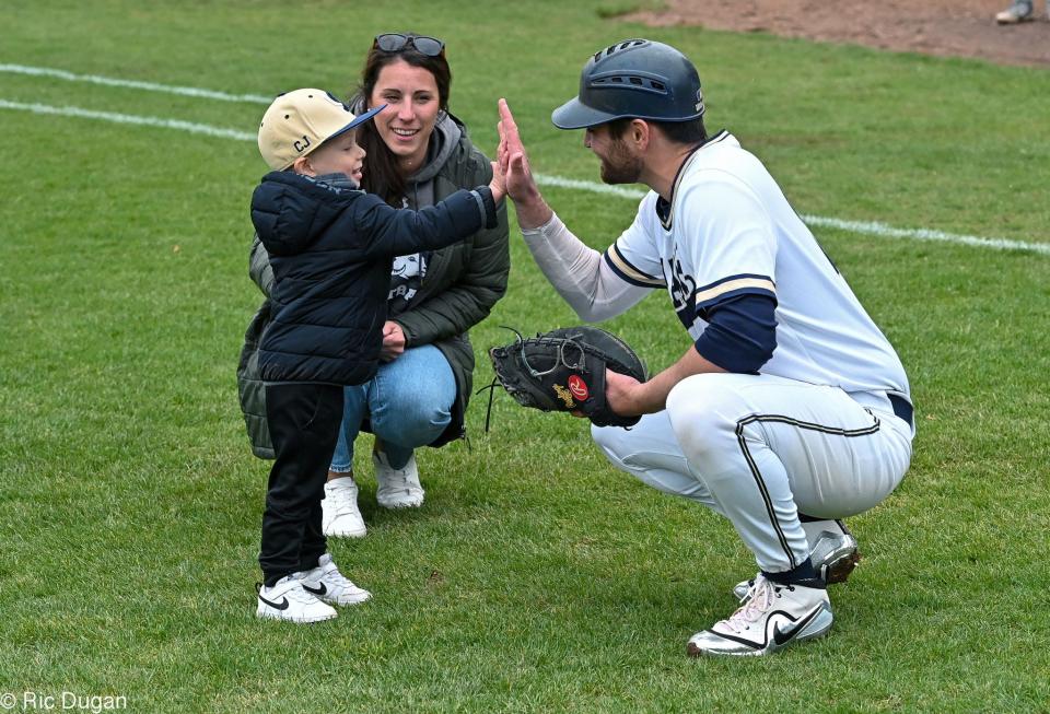 Cooper Jackson gets a high five from Shepherd catcher Andrew Edwards after Jackson threw out the first pitch before the second game of a doubleheader on Tuesday. Watching is Cooper's mother Danielle Jackson.