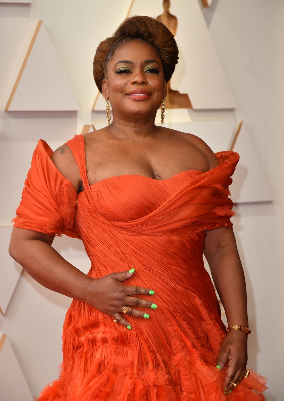 Aunjanue Ellis-Taylor standing on the red carpet wearing an off-shoulder ruched dress with layered skirt, accessorized with bracelets