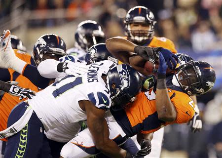 Broncos' Moreno is tackled by Seahawks' Clemons during the NFL Super Bowl XLVIII football game in East Rutherford