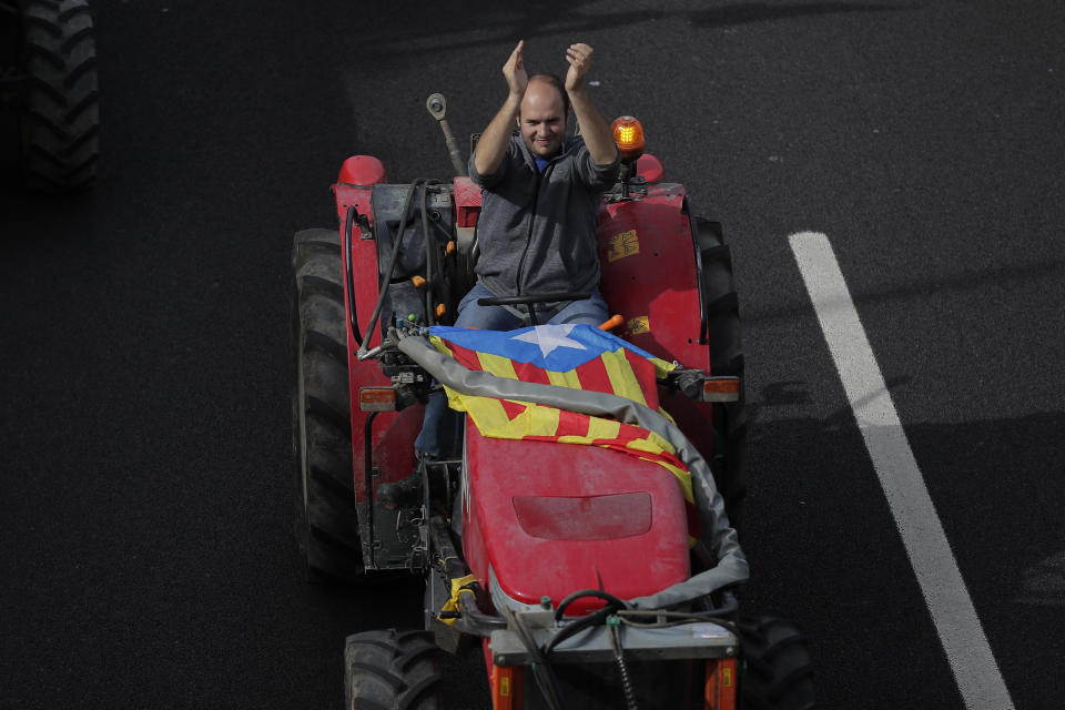 A protester with an "estelada" or independence flag applauds as he drives a tractor entering the city on the fifth day of protests over the conviction of a dozen Catalan independence leaders in Barcelona, Spain, Friday, Oct. 18, 2019. Various flights into and out of the region are cancelled Friday due to a general strike called by pro-independence unions and five marches of tens of thousands from inland towns are expected converge in Barcelona's center on Friday afternoon for a mass protest with students to and workers who are on strike. (AP Photo/Manu Fernandez)