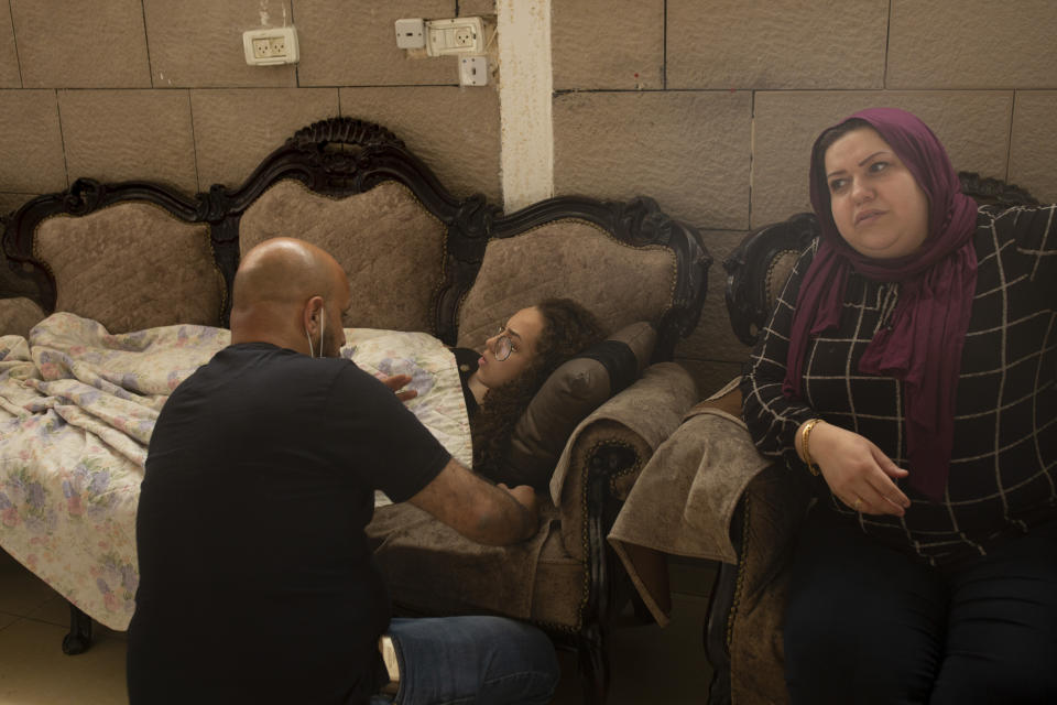 Palestinian teen Jana Kiswani, center, talks to her father, Mohammed, as she recovers in her family home after being hit by a rubber coated bullet fired by Israeli police in the Sheikh Jarrah neighborhood of east Jerusalem, where her family is threatened with eviction from their home by Israeli settlers, Wednesday, May 26, 2021. (AP Photo/Maya Alleruzzo)