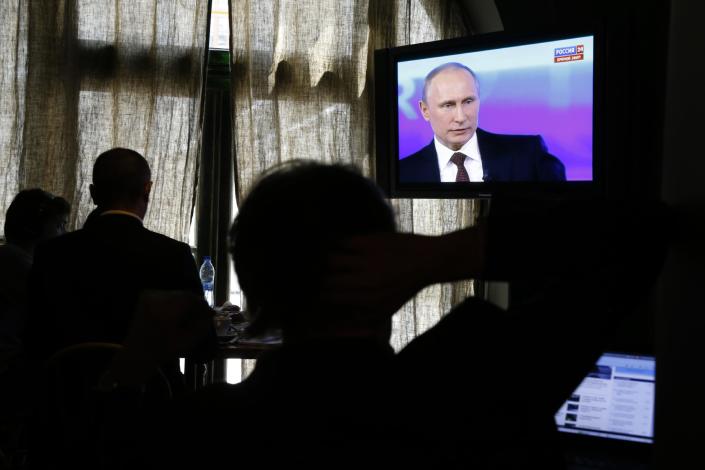 Reporters listen to Russian President Vladimir Putin's speech, displayed on TV screens during a nationally televised question-and-answer session in Moscow, Thursday, April 17, 2014. Russia's President Vladimir Putin on Thursday dismissed claims that Russian special forces are fomenting unrest in eastern Ukraine as "nonsense," but expressed hope for success of four-way talks on settling the crisis. (AP Photo/Pavel Golovkin)