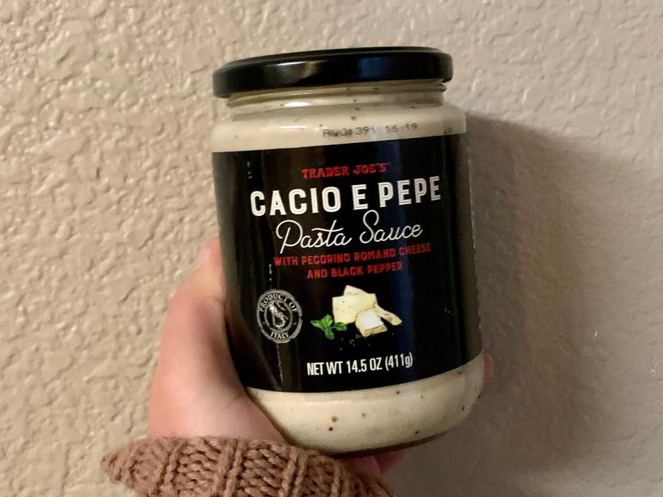 The writer holds a jar of Trader Joe's cacio e pepe