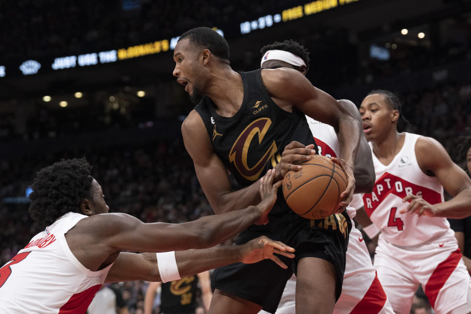 Cleveland Cavaliers' Evan Mobley, center, looks to pass the ball after being crowded by the Toronto Raptors defense during first-half NBA basketball game action in Toronto, Monday, Nov. 28, 2022. (Chris Young/The Canadian Press via AP)