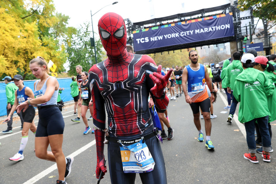 A runner in a Spider-Man suit poses after crossing the finish line of the 2022 New York City Marathon on Sunday.