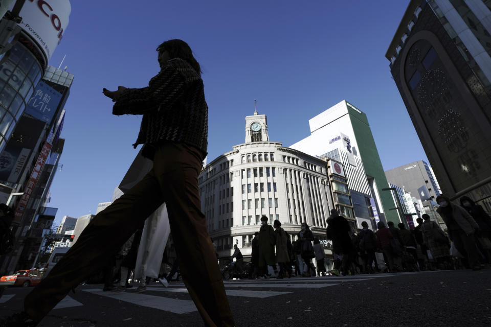 People wearing protective masks to help curb the spread of the coronavirus use a pedestrian crosswalk at the Ginza shopping street Thursday, Dec. 17, 2020, in Tokyo. The Japanese capital confirmed more than 800 new coronavirus cases on Thursday. (AP Photo/Eugene Hoshiko)