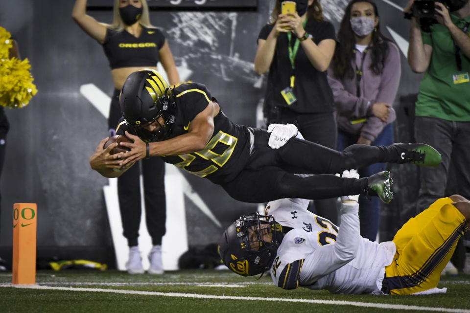 Oregon running back Travis Dye (26) dives into the end zone over California safety Daniel Scott (32) during the second quarter of an NCAA college football game Friday, Oct. 15, 2021, in Eugene, Ore. (AP Photo/Andy Nelson)