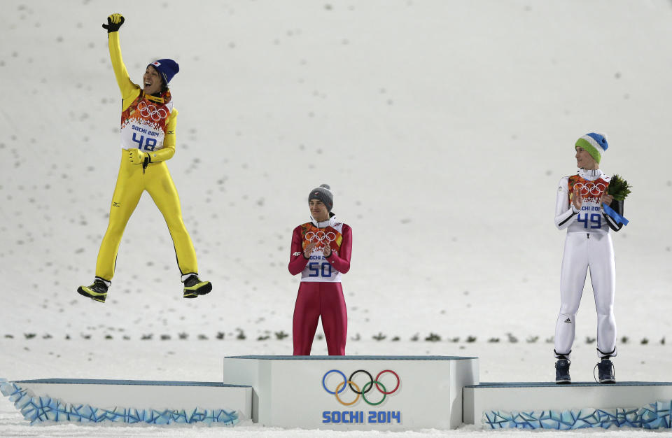 Japan's Noriaki Kasai celebrates winning the silver as Poland's gold medal winner Kamil Stoch and Slovenia's bronze medal winner Peter Prevc, from left, applaud during the flower ceremony after the ski jumping large hill final at the 2014 Winter Olympics, Saturday, Feb. 15, 2014, in Krasnaya Polyana, Russia.(AP Photo/Matthias Schrader)