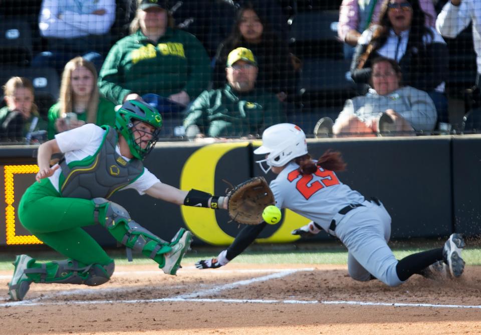 Oregon State’s Kiki Escobar, right, dives for home ahead of the throw to Oregon’s Emma Kauf during the fourth inning at Jane Sanders Stadium April 21