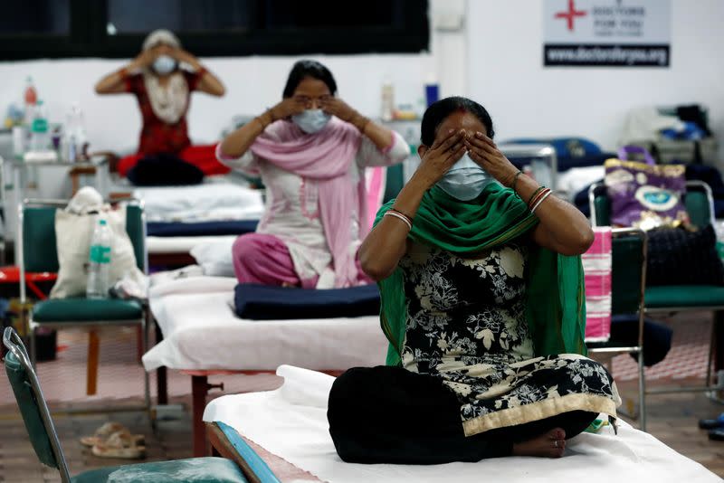 People suffering from the coronavirus disease (COVID-19) perform yoga inside a care centre for COVID-19 patients at an indoor sports complex in New Delhi