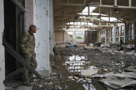 A Ukrainian serviceman looks at the ruins of the sports complex of the National Technical University in Kharkiv, Ukraine, Friday, June 24, 2022, damaged during a night shelling. The building received significant damage. A fire broke out in one part but firefighters managed to put it out. (AP Photo/Andrii Marienko)