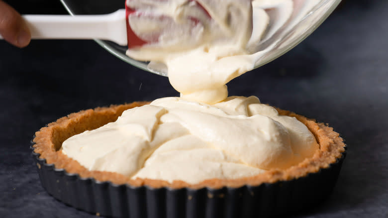 Pouring cream cheese onto crust