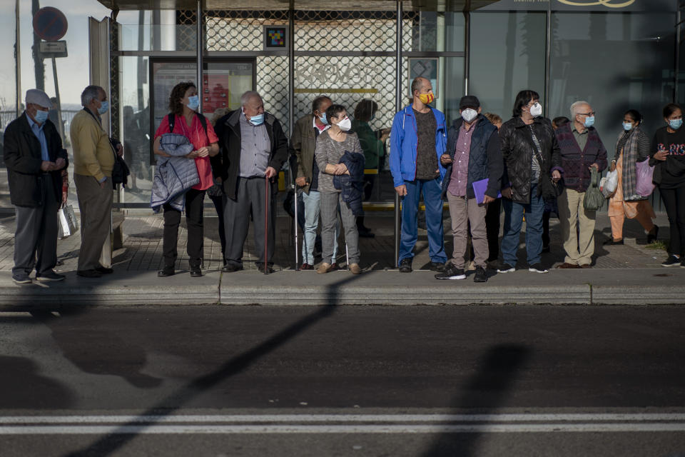 People wear face masks to protect from coronavirus as they wait for a bus in Barcelona, Spain, Friday, Oct. 23, 2020. Spain has reported 1 million confirmed infections — the highest number in Western Europe — and at least 34,000 deaths from COVID-19, although experts say the number is much higher since many cases were missed because of testing shortages and other problems. (AP Photo/Emilio Morenatti)