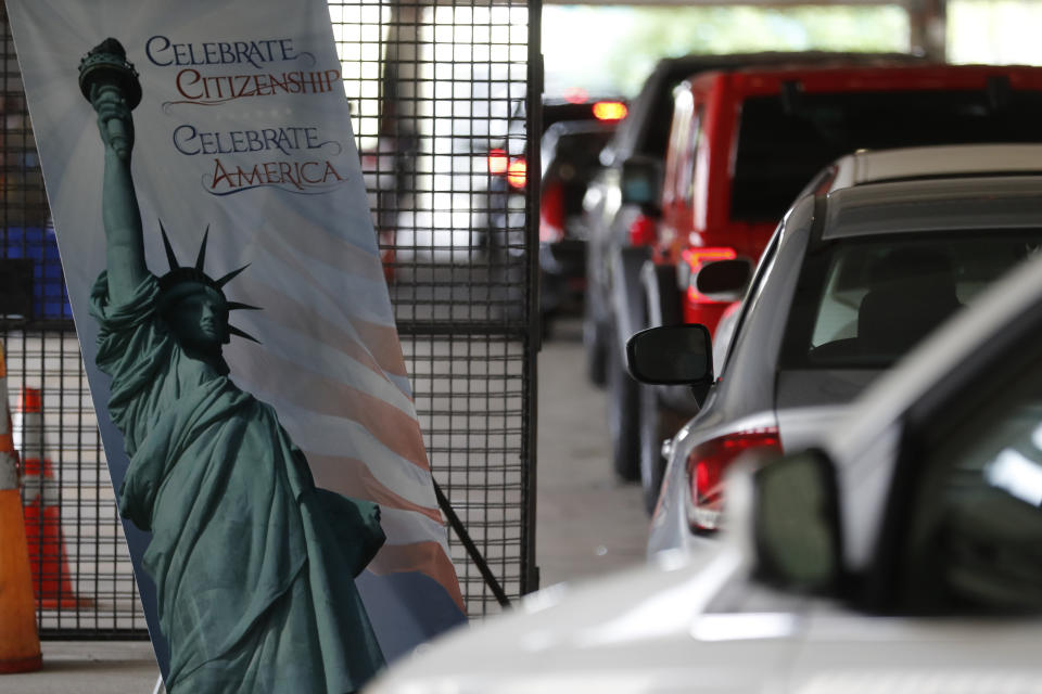 In this June 26, 2020, photo cars line up during a drive-thru naturalization service in a parking structure at the U.S. Citizenship and Immigration Services headquarters on Detroit's east side. The ceremony is a way to continue working as the federal courthouse is shut down due to Coronavirus. The U.S. has resumed swearing in new citizens but the oath ceremonies aren't the same because of COVID-19 and a budget crisis at the citizenship agency threatens to stall them again. (AP Photo/Carlos Osorio)