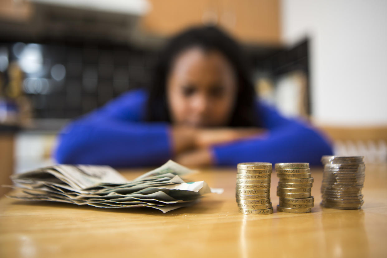 Higher interest rates make borrowing more expensive. A young lady sits at her kitchen table counting her money to pay the household bills. (Photo by In Pictures Ltd./Corbis via Getty Images)