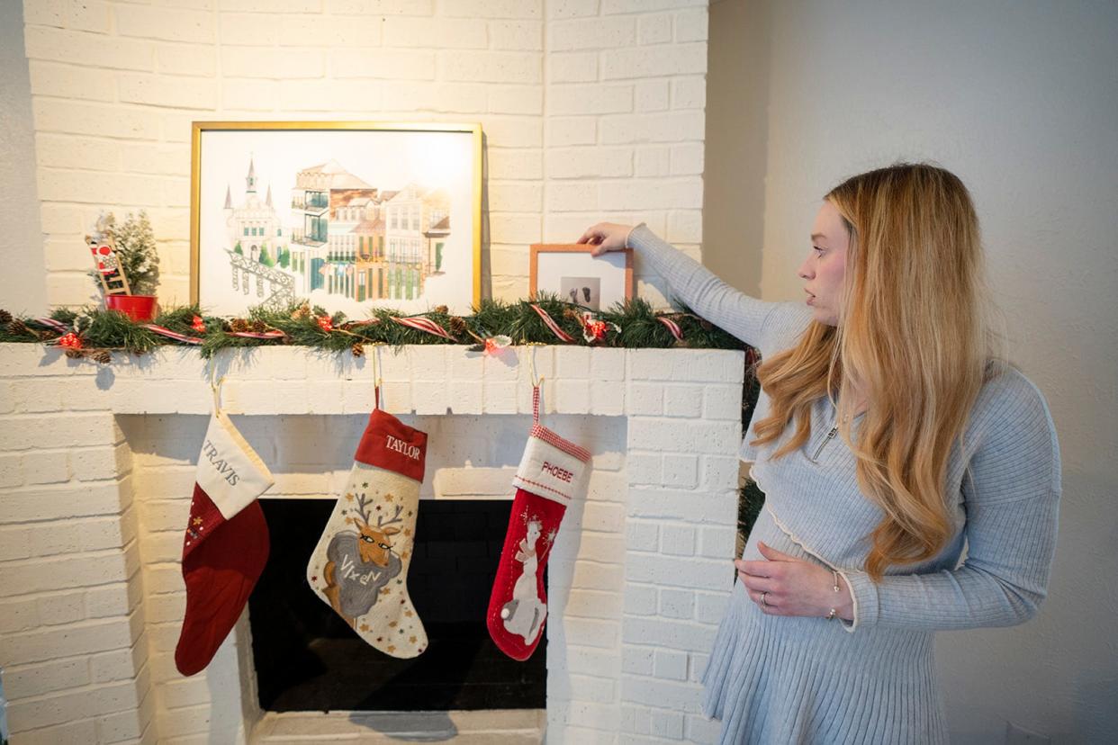 Three stockings hang on the fireplace Wednesday in Taylor and Travis Edwards' South Austin home, including one for their lost child, Phoebe, as Taylor looks at a photo of Phoebe's footprints. After years of trying to conceive through in vitro fertilization, the Edwardses received a fatal diagnosis for their baby at 17 weeks of pregnancy. They traveled out of state for an abortion.