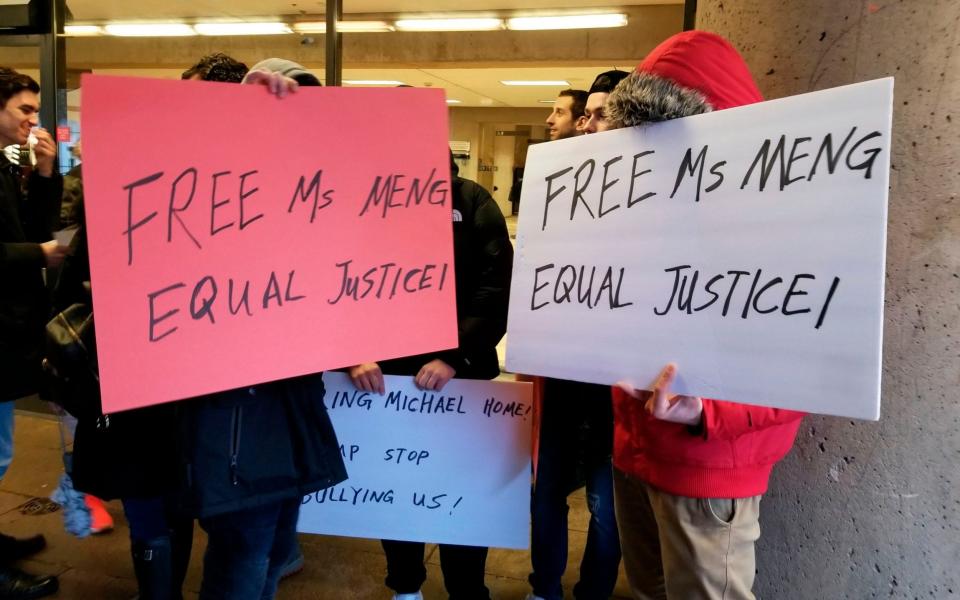 The protestors tried to hide their faces when asked questions about why they wanted Ms Meng freed - AFP