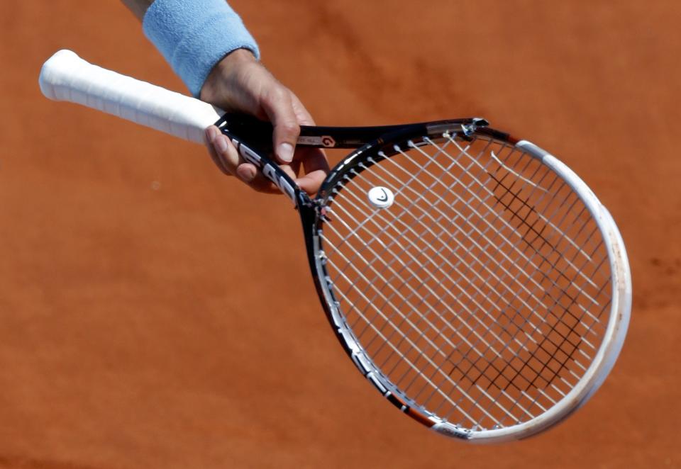 Novak Djokovic of Serbia holds his broken racket after he smashed it during his men's semi-final match against Ernests Gulbis of Latvia at the French Open tennis tournament at the Roland Garros stadium in Paris June 6, 2014. REUTERS/Jean-Paul Pelissier (FRANCE - Tags: SPORT TENNIS)