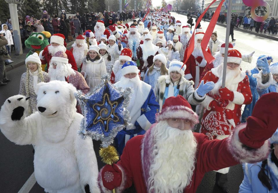 People dressed up as Father Frost, the equivalent of Santa Claus, and Snow Maiden, march as others perform in celebration of Christmas in central Minsk