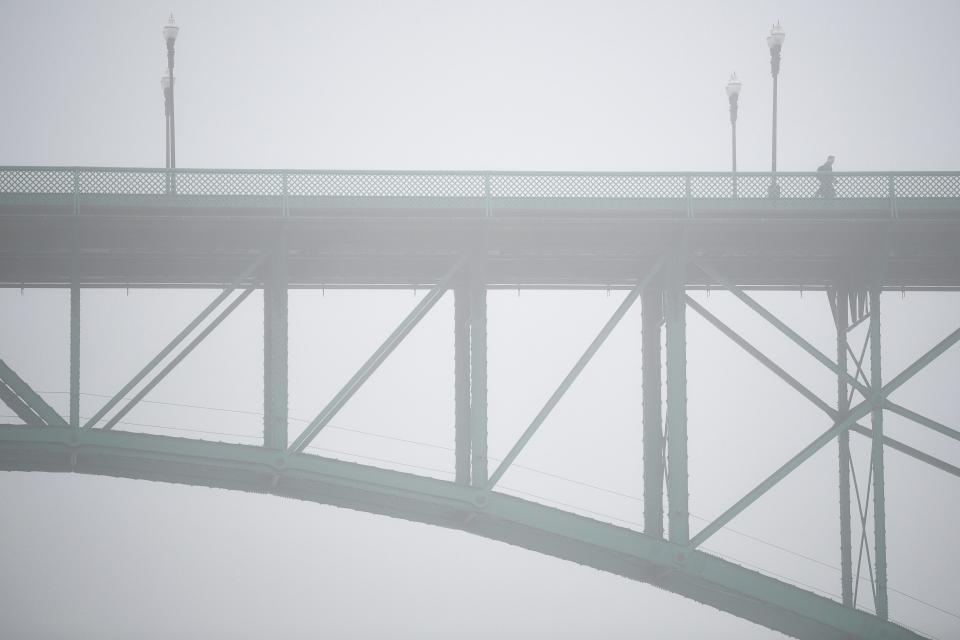 A person crosses the Gay Street Bridge on a foggy morning in Knoxville on Jan. 18.