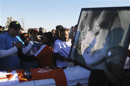 Family members and friends stand next to a coffin holding the remains of Idaly Jauche Laguna in Ciudad Juarez December 27, 2013. REUTERS/Jose Luis Gonzalez