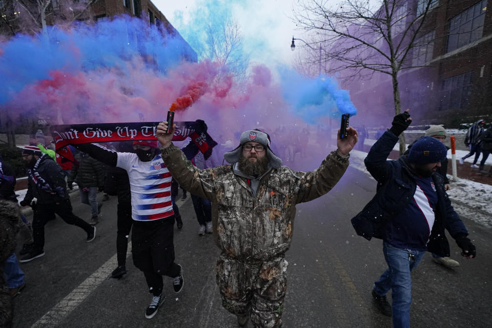 Scott Spencer holds colorful flares as he and a group of United States men's national soccer team supporters march to Lower.com Field ahead of a FIFA World Cup qualifying soccer match against El Salvador, Thursday, Jan. 27, 2022, in Columbus, Ohio. (AP Photo/Julio Cortez)