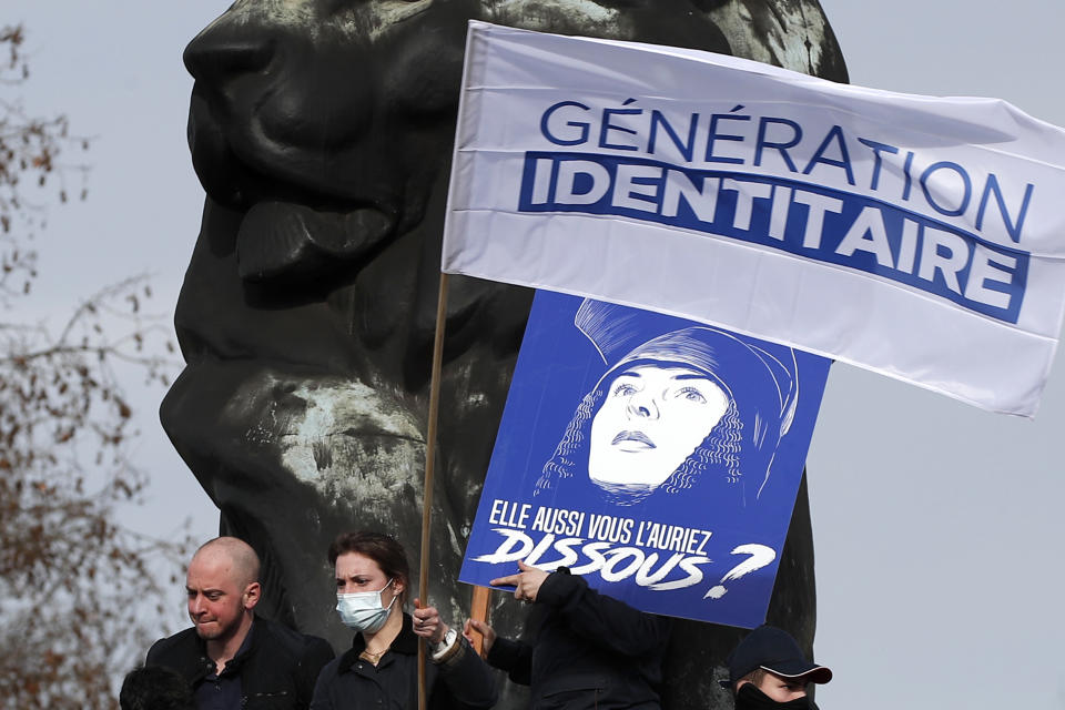 FILE - In this Feb.20, 2021 file photo, supporters of the group Generation Identity hold a banner reading "Man does not dissolve a generation" during a demonstration in Paris. Generation Identity has influence throughout France and beyond. It contends its members are whistle-blowers on a mission to preserve French and European civilization, seen as undermined by newcomers, notably Muslims. (AP Photo/Francois Mori, File)