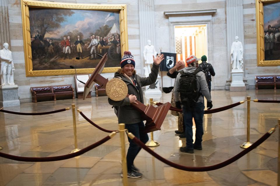 A pro-Trump protester, who has been identified as Adam Johnson of Parrish, carries the lectern of U.S. Speaker of the House Nancy Pelosi through the Rotunda of the U.S. Capitol Building after a pro-Trump mob stormed the building on Wednesday.