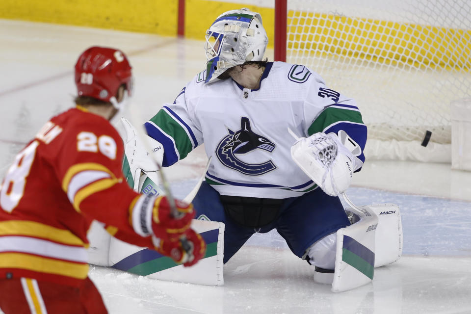 Vancouver Canucks goalie Spencer Martin, right, gives up a goal to Calgary Flames' Elias Lindholm during the second period of an NHL hockey game Saturday, Dec. 31, 2022, in Calgary, Alberta. (Larry MacDougal/The Canadian Press via AP)