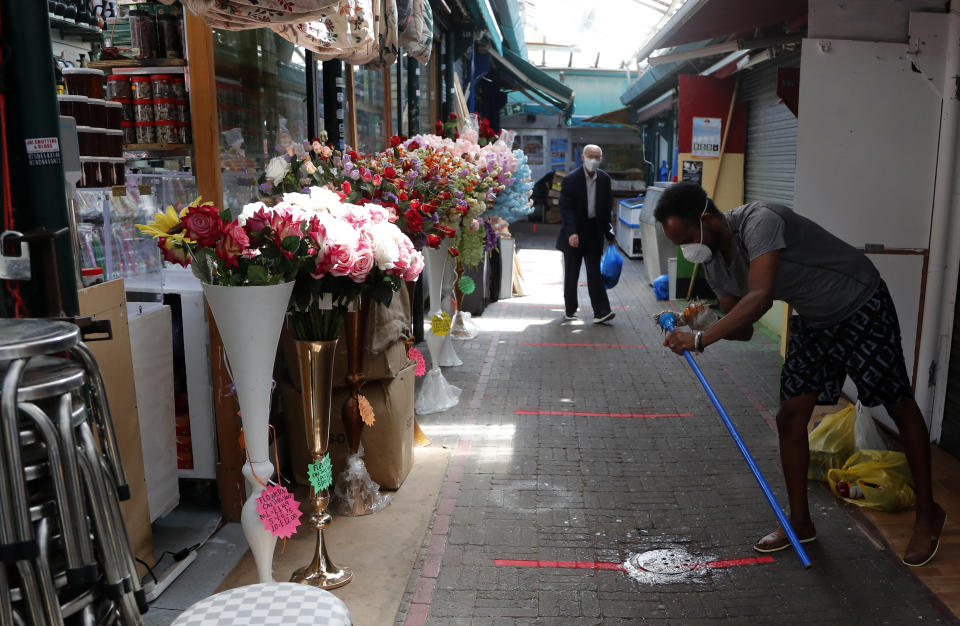 With social distancing guideline marking on the pavement, customers stroll through Shepherd's bush market that is allowed to reopen after the COVID-19 lockdown in London, Monday, June 1, 2020. The British government has lifted some lockdown restrictions to restart social life and activate the economy while still endeavouring to limit the spread of the highly contagious COVID-19 coronavirus. (AP Photo/Frank Augstein)