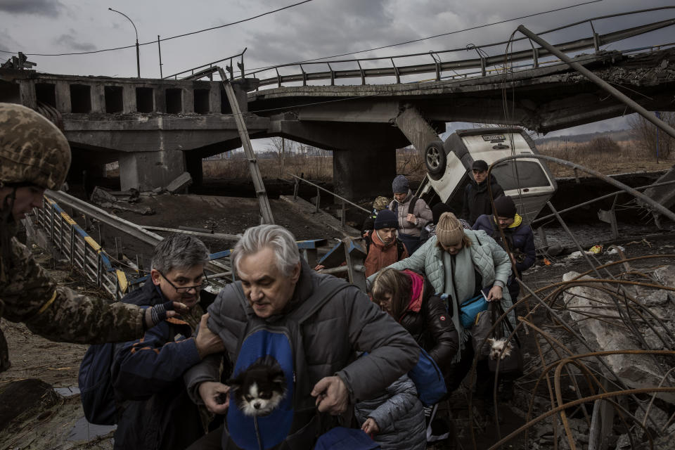 Civilians cross a destroyed bridge as they evacuate the city of Irpin