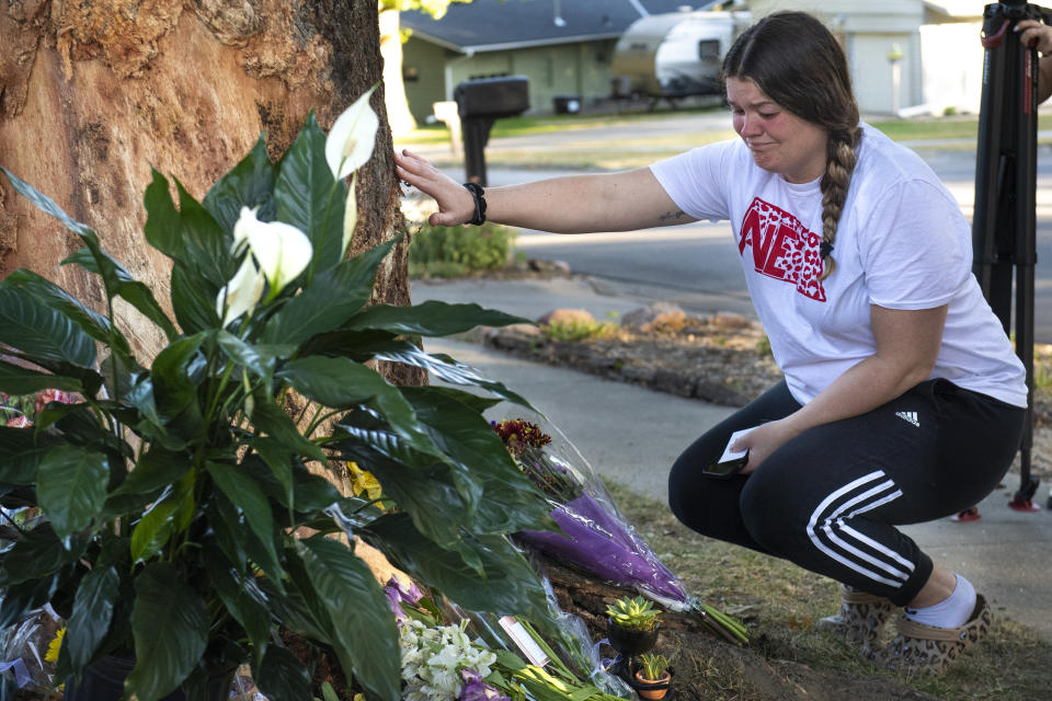 Kayla Kelly grieves as mourners gather and lay flowers and gifts at the site of a deadly car crash during an impromptu memorial service on Sunday, Oct. 2, 2022, in Lincoln, Neb. Police in Nebraska said a passenger’s cellphone automatically alerted responders after a car hit the tree in a crash that killed all of its young occupants. (Kenneth Ferriera/Lincoln Journal Star via AP)