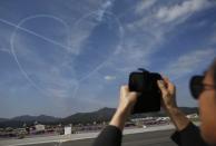 A man takes photographs of a heart-shaped contrail left in the sky by the Black Eagles South Korean Air Force aerobatic team during celebrations to mark the 65th anniversary of Korea Armed Forces Day, at a military airport in Seongnam, south of Seoul, October 1, 2013. (REUTERS/Kim Hong-Ji)