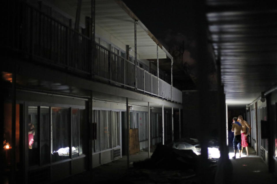 Residents use flashlights to navigate the dark walkways at night at the damaged American Quality Lodge where they continue to live in the aftermath of Hurricane Michael, in Panama City, Fla., Tuesday, Oct. 16, 2018. Nighttime means relief from the heat, yet it also brings the threat of looters, who residents say have taken money, jewelry, food and even rain-soaked clothes from rooms ripped apart and left open to the elements by Michael. (AP Photo/David Goldman)