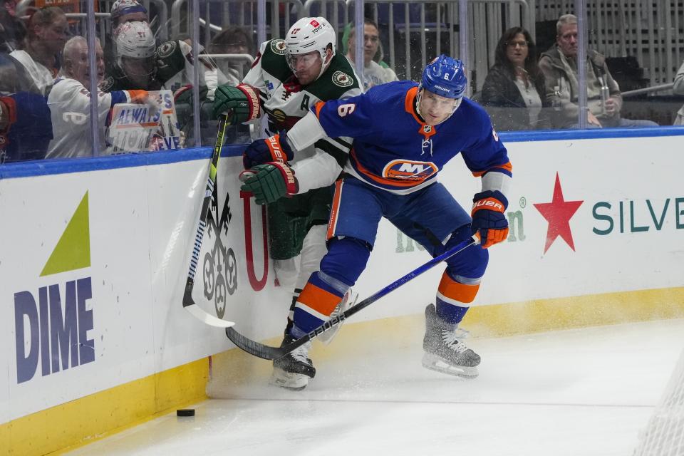 Minnesota Wild's Marcus Foligno (17) fights for control of the puck with New York Islanders' Ryan Pulock (6) during the first period of an NHL hockey game Tuesday, Nov. 7, 2023, in Elmont, N.Y. (AP Photo/Frank Franklin II)