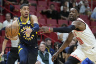 Indiana Pacers guard Tyrese Haliburton, left, passes around Miami Heat center Bam Adebayo (13) during the first half of an NBA basketball game, Wednesday, Feb. 8, 2023, in Miami. (AP Photo/Wilfredo Lee)